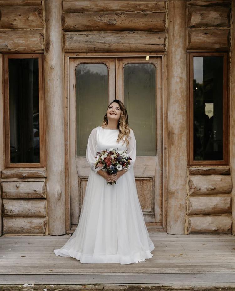 meghan Timeless Elegance – Crepe & Chiffon A-Line Wedding Gown A beautiful fusion of graceful sophistication and modern charm, this crepe and chiffon A-line wedding gown is designed for the bride who desires effortless elegance with delicate detailing. ✨ Design Highlights: ✔ Bateau neckline – A refined and timeless feature that exudes sophistication. ✔ Sheer long sleeves – Adding a touch of romance and ethereal beauty. ✔ Crepe bodice – Smooth and structured for a flawless, polished look. ✔ Flowing tulle A-line skirt – Lightweight and airy, creating a dreamy silhouette. ✔ Wide horsehair hemline – Enhancing movement and definition for a striking finish. 💫 Customization Options: ✅ Made to measure for the perfect fit. ✅ Available in your preferred colour. ✅ Choose a long or short train to match your vision. ✅ Option for short or long sleeves for added versatility. ✅ Personalize it with or without a slit for a modern or classic touch. 👑 A gown for the bride who embraces elegance, movement, and timeless beauty. 👑 📞 Custom orders available! 📧 info@bestersbridal.co.za | 📱 084 268 1354