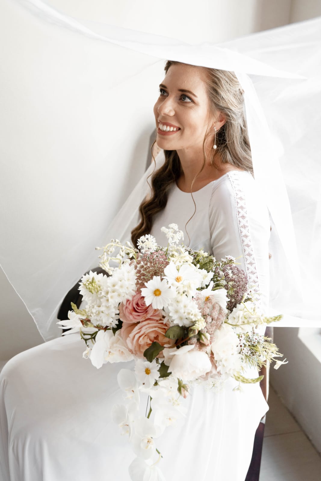 inge Boho-Inspired Chiffon & Lace A-Line Wedding Gown with Bishop Sleeves The Inge gown is effortlessly romantic, perfect for the bride who dreams of soft movement, boho charm, and timeless lace detail. Crafted from flowing chiffon and delicate Chantilly lace, this dress radiates grace with every step. ✨ Design Highlights: ✔ Bateau Neckline – A high, elegant neckline that frames the collarbone and exudes classic femininity. ✔ Sheer Chantilly Lace Back – A breathtaking illusion back with intricate lace detail and a delicate bridal button closure. ✔ Flowy A-Line Chiffon Skirt – Lightweight and soft, perfect for movement and comfort with a relaxed silhouette. ✔ Bishop Sleeves with Boho Lace – Long, airy sleeves gathered at the wrist with wide boho lace trim for a free-spirited yet refined look. ✔ Long Flowing Train – Adds ethereal beauty and soft bridal drama as you walk down the aisle. 💫 Customization Options: ✅ Custom sizing to ensure the perfect fit ✅ Option to adjust neckline or remove sleeves ✅ Available in soft white, ivory, or off-white chiffon and lace ✅ Add a matching veil with Chantilly lace trim 🌾 Inge is designed for the bride who wants to feel light, romantic, and a little whimsical—with textures and details that move with the breeze. 🌾 📞 Book your consultation or fitting today! 📧 info@bestersbridal.co.za | 📱 084 268 1354