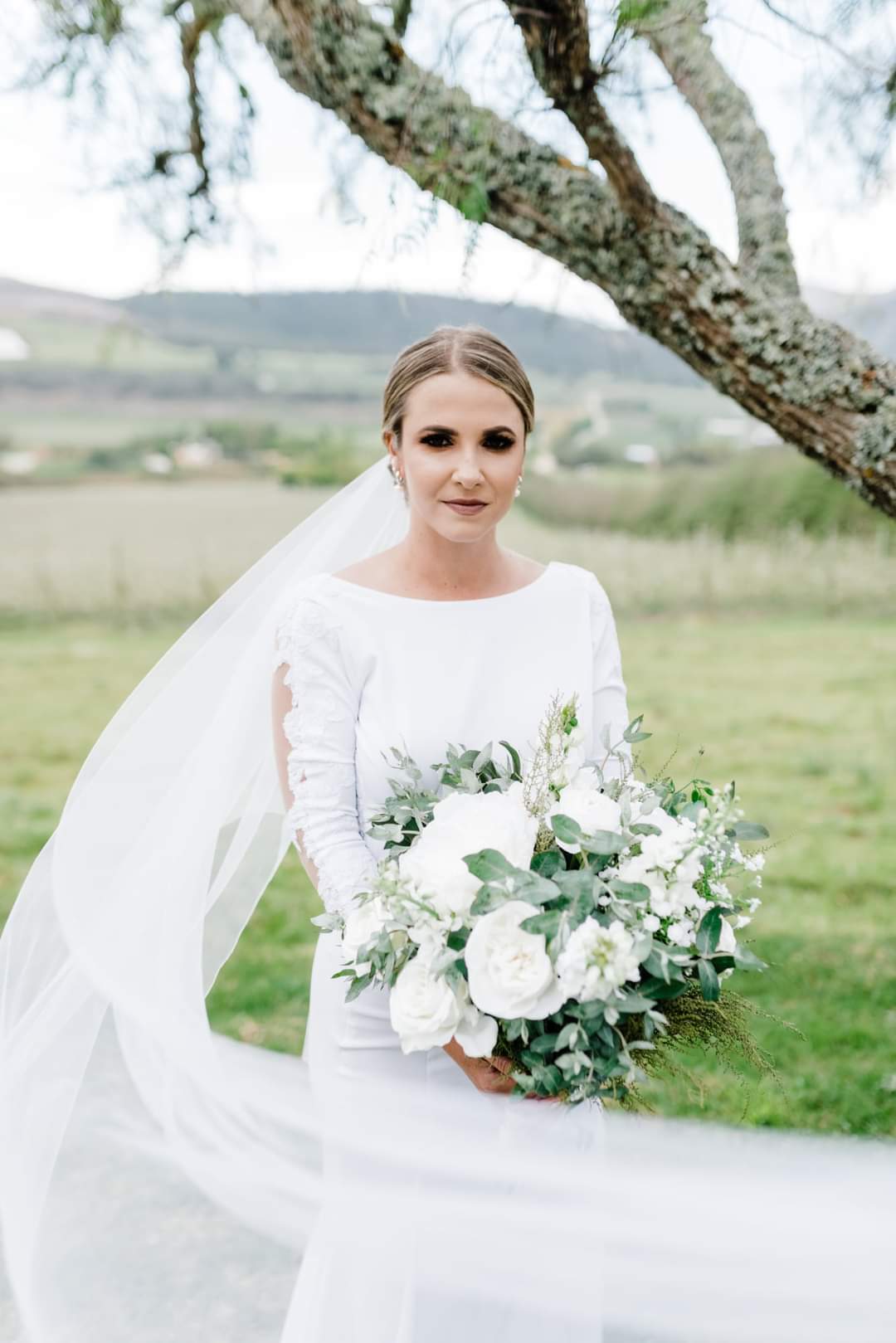 Jo-Ann Graceful Lace & Crepe Long-Sleeve Bridal Gown A perfect blend of timeless elegance and modern sophistication, this exquisite bridal gown is designed for the bride who desires a classic yet captivating look. ✨ Design Highlights: ✔ Bateau neckline – A refined and elegant touch that enhances the décolletage. ✔ Long lace sleeves – Delicate and romantic, perfect for a sophisticated bridal style. ✔ Fitted bodice with a fit-and-flare silhouette – Designed to accentuate the figure while allowing graceful movement. ✔ Open lace back bodice – A stunning detail that adds a touch of allure. ✔ Long train – A breathtaking finish for a truly unforgettable entrance. 💫 Customization Options: ✅ Made to measure for the perfect fit. ✅ Available in your preferred colour. ✅ Choose a long or short train to match your vision. ✅ Option for short or long sleeves for added versatility. ✅ Personalize it with or without a slit for a modern or classic touch. 👑 A gown for the bride who embodies grace, sophistication, and timeless beauty. 👑 📞 Custom orders available! 📧 info@bestersbridal.co.za | 📱 084 268 1354