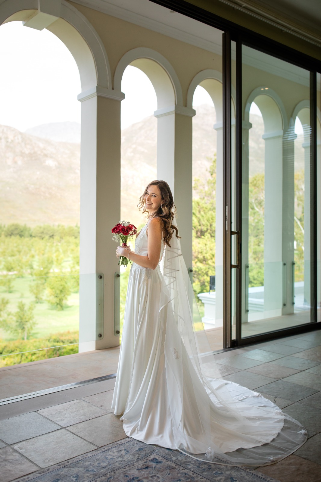 angie Satin A-Line Gown with Deep Plunge & Beaded Lace Details The Angie gown is a striking combination of modern glamour and timeless elegance. With its dramatic deep V neckline and soft satin shine, this gown is designed to make a bold yet sophisticated bridal statement. Delicate beaded lace appliqués add texture and shimmer, while the full flare skirt ensures graceful movement down the aisle. ✨ Design Highlights: ✔ Deep Plunge V-Neckline – A bold neckline softened with a nude tulle insert between the bust for comfort and coverage. ✔ Thin Beaded Lace Straps – Dainty yet detailed, offering a touch of sparkle while keeping the look light and refined. ✔ Embellished Lace Bodice – Intricately adorned with hand-placed beaded lace appliqués for a luxurious finish. ✔ Nude Tulle Side Inserts – Subtle inserts under the arms for breathability and a sleek silhouette. ✔ Full-Flare Satin A-Line Skirt with Pockets – A classic bridal shape with modern touches, designed for both style and practicality. ✔ Long Flowing Train – Creates a dramatic, elegant entrance. ✔ Button Closure at Back – A timeless bridal finish that adds polish and charm. 💫 Customization Options: ✅ Custom sizing for the perfect fit ✅ Option to raise or soften the neckline ✅ Available in soft white or ivory satin ✅ Add a matching veil or lace bolero for styling versatility ✨ Angie is perfect for the bride who wants shine, structure, and a touch of sparkle—wrapped in a silhouette that flatters and flows. ✨ 📞 Book your consultation or fitting now! 📧 info@bestersbridal.co.za | 📱 084 268 1354 Satin A-Line • Deep V Neck • Beaded Lace Straps & Bodice • Pockets • Long Train • Button Closure