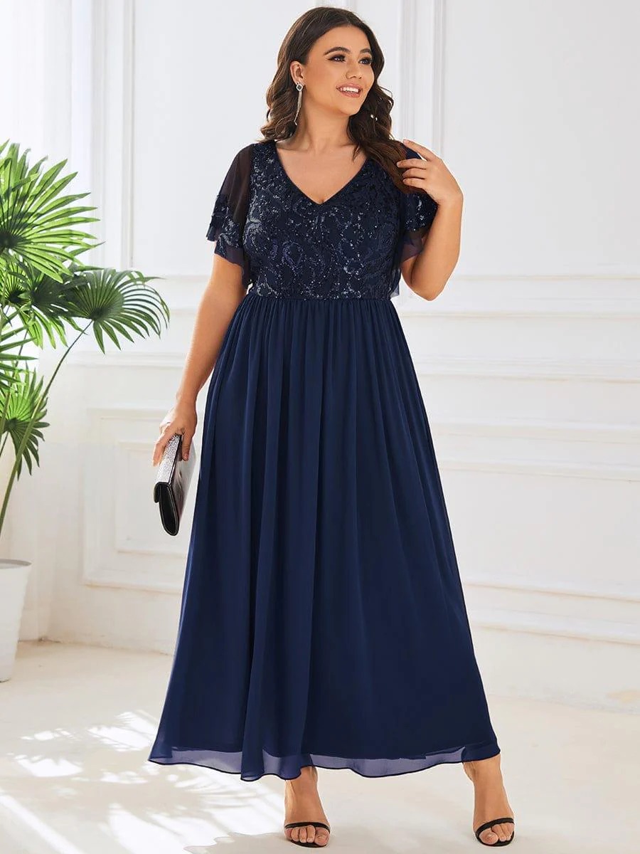 Hazel A sophisticated Mother of the Bride dress featuring a sparkling sequin V-neck bodice, soft short sleeves, and a smooth, flowing skirt for timeless elegance. This dress is not currently in stock but is available to order.